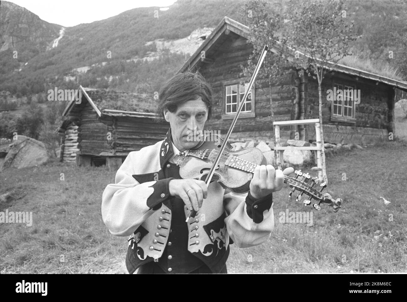 Osa spielt harding fiddle mit wasserfall im hintergrundfoto Fotos und