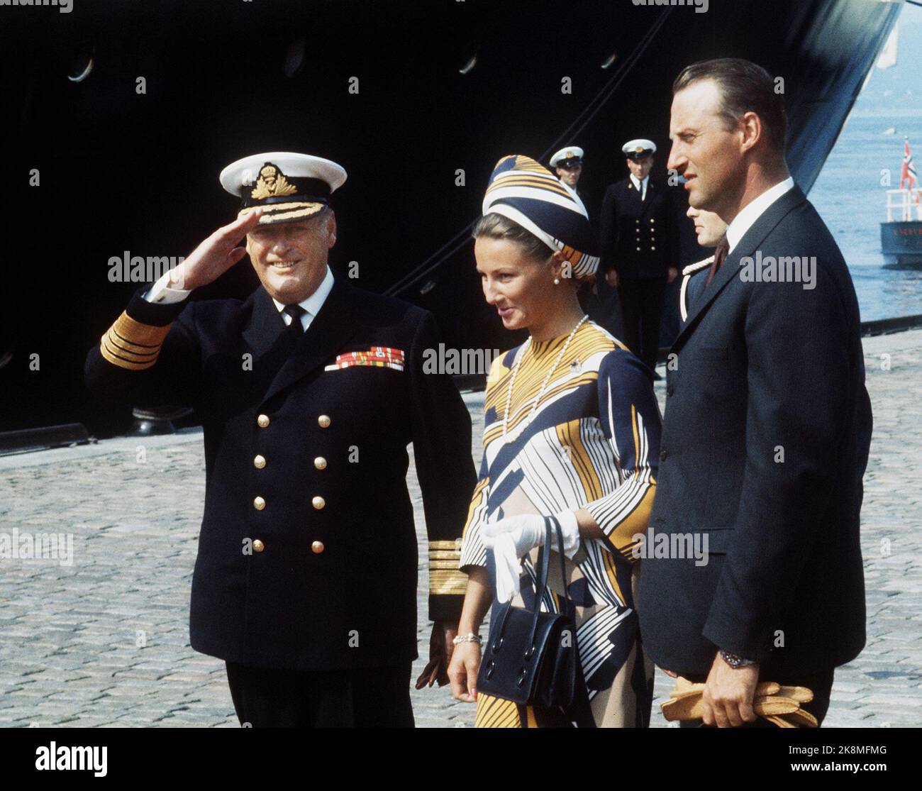 Bergen 19690807. Königin Elizabeth in Norwegen mit der Familie. Königin Elizabeth kommt mit 'Britannia' in Bergen an. König Olav, Kronprinzessin Sonja und Kronprinz Harald heißen die Königin in Bergen willkommen. Roter Teppich. Gelb, weiß und schwarz gemustertes Kleid gleich in Hut. Schwarze Tasche und Schuhe, Perlenkette. Ernst. Foto: NTB Archive bat König Olav, in Norwegen Dias zu reisen. Stockfoto