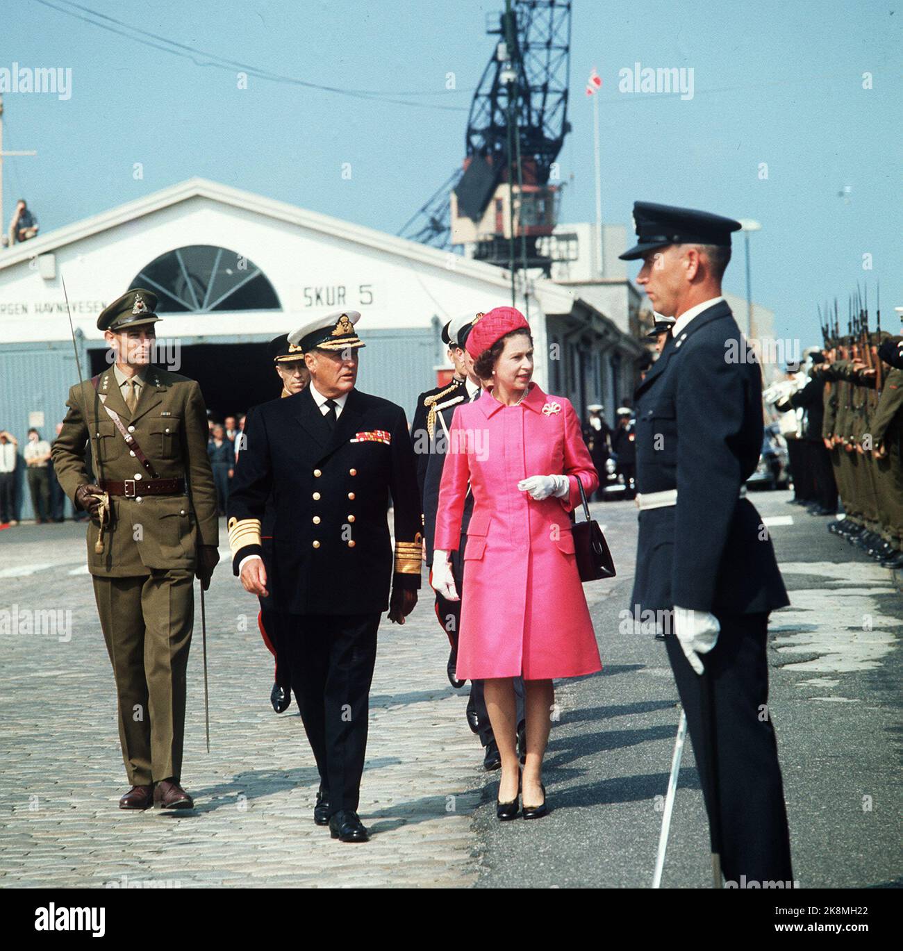 Bergen 19690807. Königin Elisabeth II. Bei einem Staatsbesuch in Norwegen mit der Familie. König Olav begrüßt Dronnigen in Bergen. Hier inspiziert der königliche Ehrenhof bei der Ankunft. Die Königin in rotem Mantel und rotem Hut. Schwarze Tasche und Schuhe. Ernst. NTB-Archiv/ntb Stockfoto