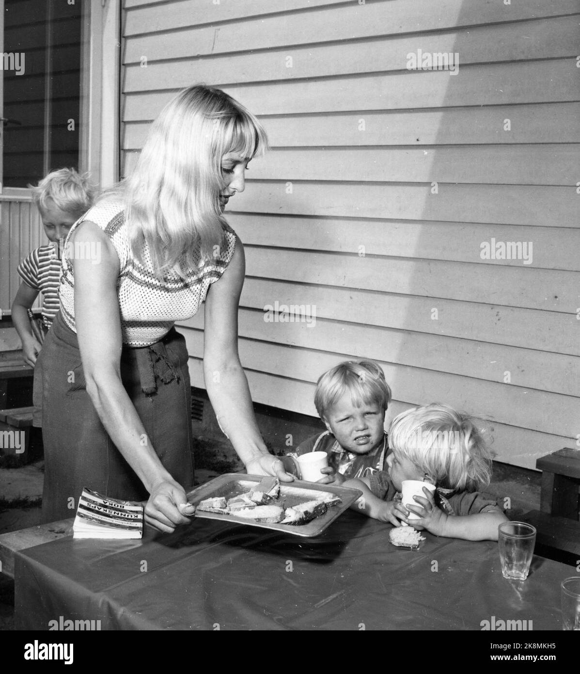 Oslo 19540904. In Edvard Munchs Ehely bei Skøyen wird noch Kunst geschaffen. Nach dem Krieg wurde das große Grundstück parzelliert, um an Land für Künstlerhäuser zu kommen. Bis heute wurden 29 Künstlerfamilien in schöne, moderne Häuser umgezogen, die meisten dieser Art von Haus mit zugehörigen Studios, und mehrere Wohnungen sind entworfen. Die Künstlerkolonie ist die einzige Welt. Die junge Künstlergesellschaft arbeitete viele Jahre lang an der Studiohülle, dreht sich aber erst nach dem Krieg um Weihnachten. Hier sehen wir Sossen Krohg, der an einem Sommertag auf der Terrasse Essen für Kinder serviert. Foto: Aage Storløkken / Aktuell / NTB Stockfoto