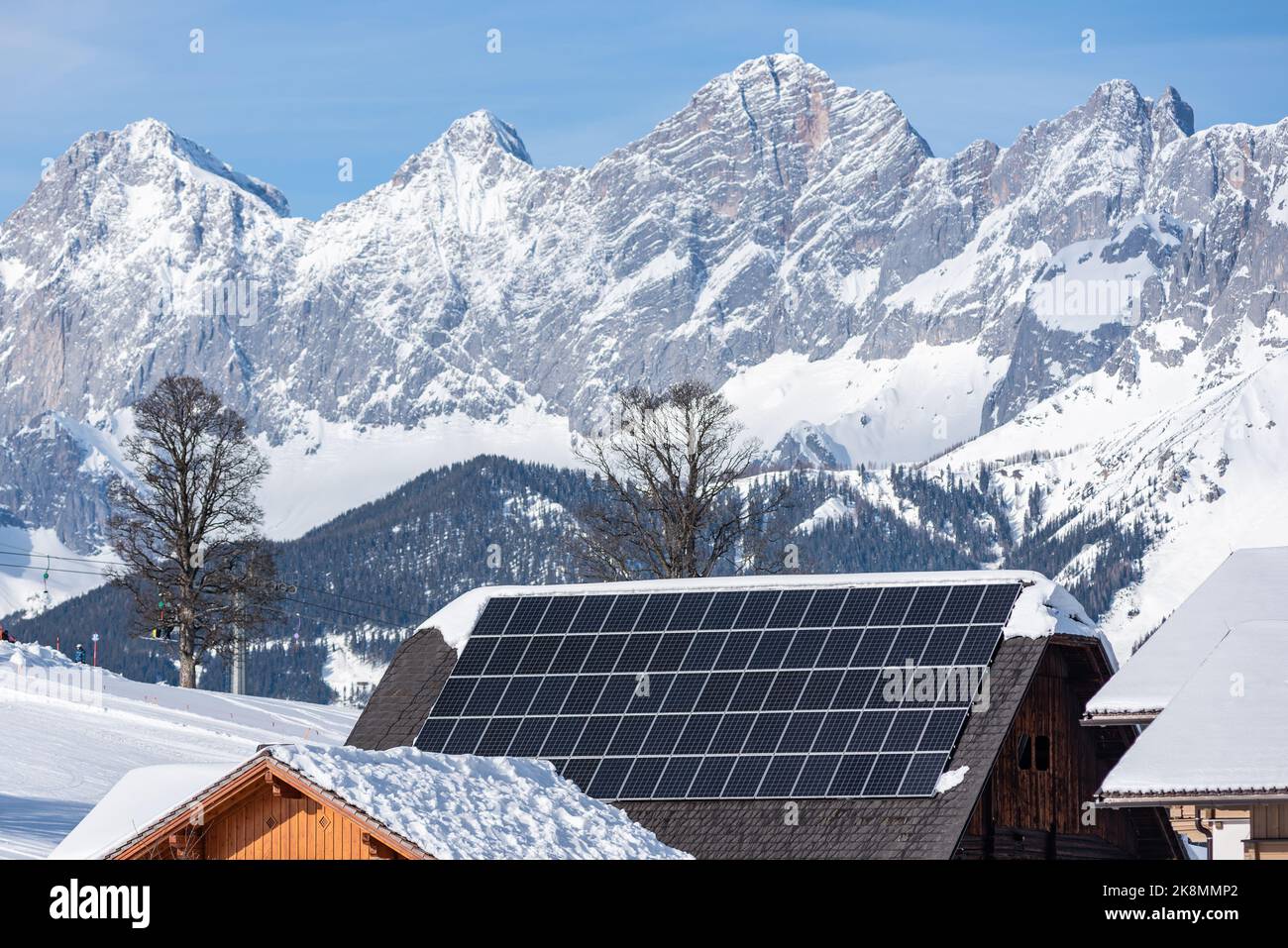 Eine Solaranlage auf einem Hausdach mit einem schneebedeckten Berg Stockfoto