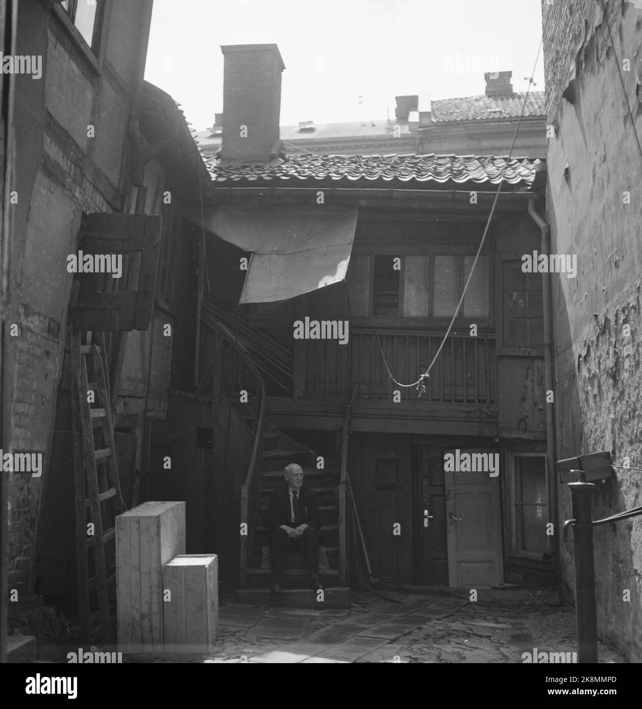 Oslo 19510609 Oslo. Hinterhof in Oslo. Ein Mann sitzt auf der Treppe. Das Holzgebäude befindet sich in einem starken Verfall und beruht auf einem städtischen Ziegelbauernhof. Auf dem Bild. Foto: Stage / NTB / NTB Stockfoto