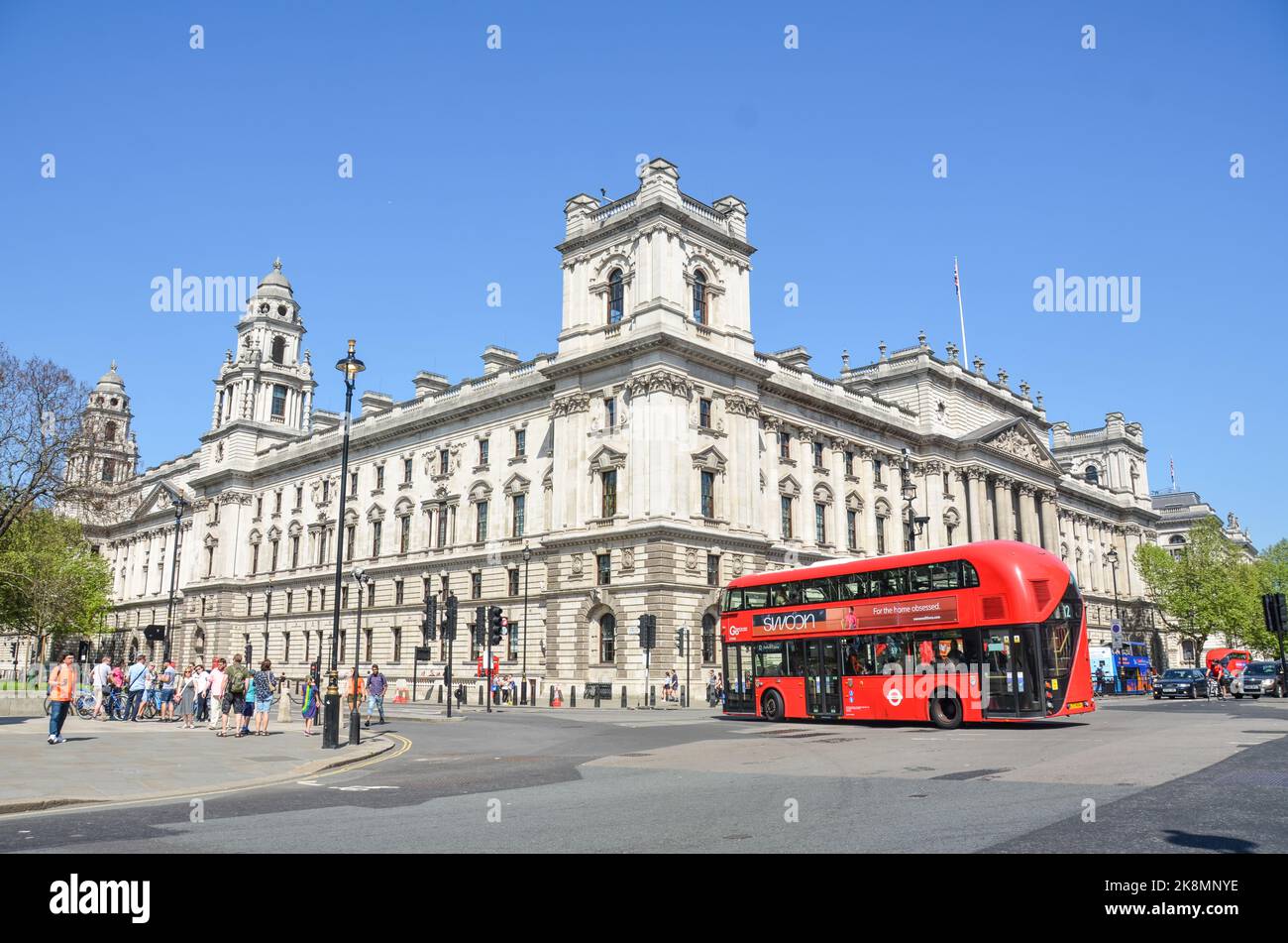 Die Straßen von London, Großbritannien, mit dem Regierungsgebäude, Menschen, die zu Fuß gehen und einem roten Bus. Stockfoto