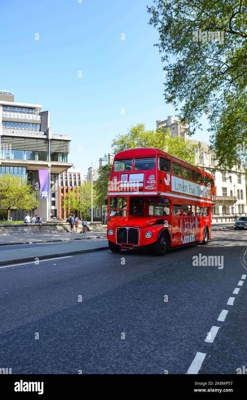 Eine vertikale Aufnahme eines roten britischen Busses mit der Stadt und den Menschen im Hintergrund. Stockfoto