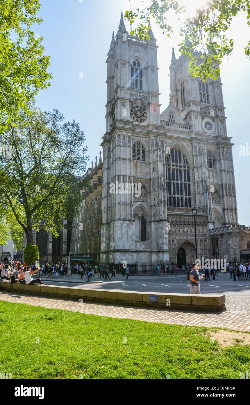Eine vertikale Aufnahme der Westminster Abbey Kathedrale an einem sonnigen Tag mit Menschen und einem Park. Stockfoto
