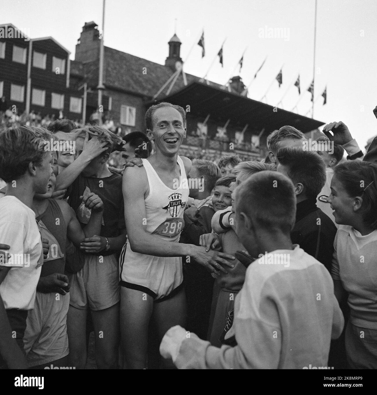 Oslo 19550825 Athletics Conference in Bislett, und wie immer steht Audun Boysen im Mittelpunkt. Hier ein lächelnder boysen, umgeben von glücklichen jungen Athleten, die zu ihrem großen Helden aufschauen. Foto: NTB / NTB Stockfoto