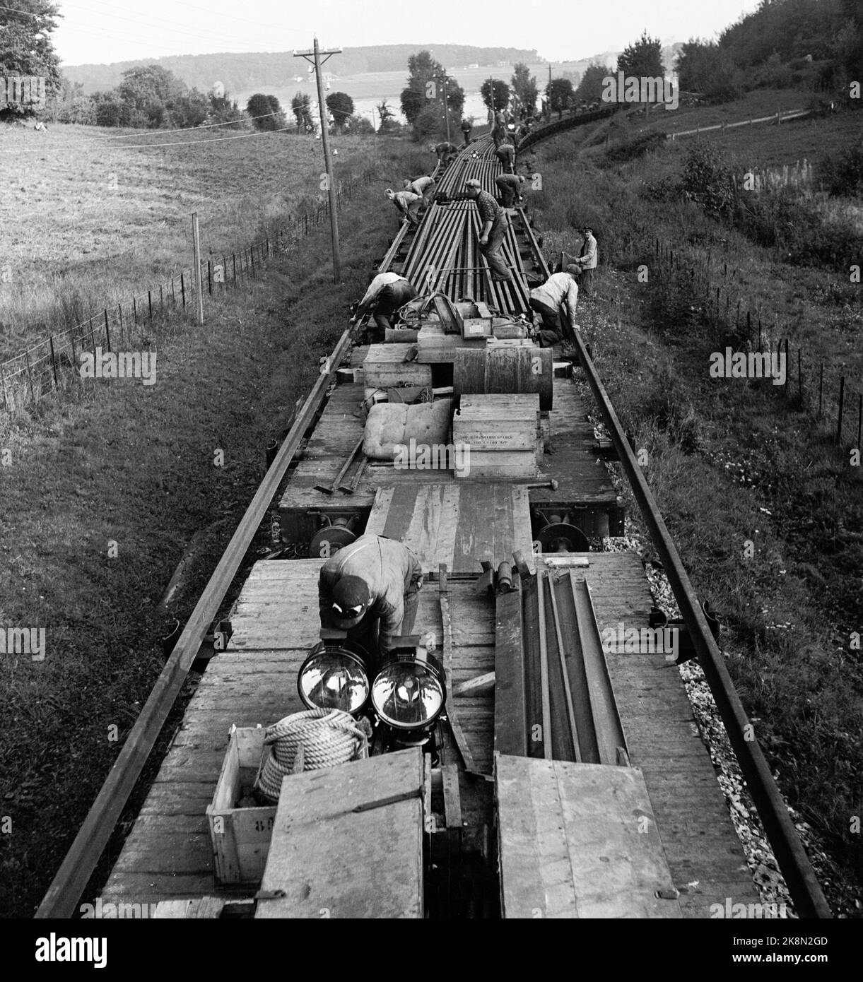 Vestfold September 1949: Die Arbeiten an der Vestfoldbanen-Eisenbahnlinie nähern sich ihrem Ende. Die Arbeiten laufen parallel zu den laufenden Zügen. Hier sind die Bahnarbeiter im Gleiszug dabei, Schienen auszulegen. Die Schienen wurden neun und neun zusammengehakt und vom Wagen gezogen, während der Eisenbahnzug vorwärts fuhr. Foto: Sverre A. Børretzen / Aktuell / NTB Stockfoto