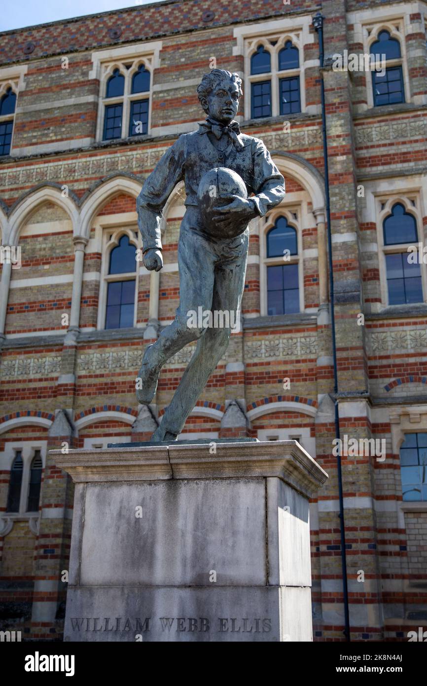 Eine vertikale Nahaufnahme der Skulptur von William Webb Ellis vor einem Gebäude an einem sonnigen Tag Stockfoto