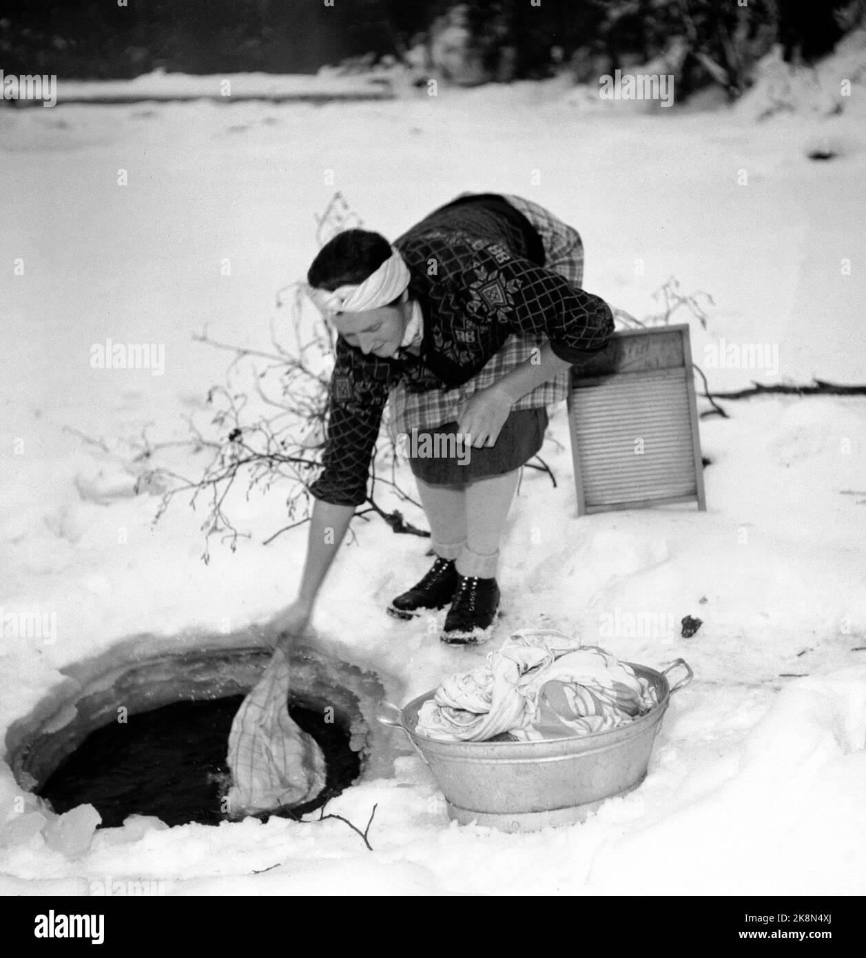 HEDMARK vinteren 1948. Vannmangel på Østlandet etter tørkesommeren 1947.  Gårdsbrukene må hente vann i elvene eller få tilkjørt vann Fra meieriene.  Her vasker en kvinne klær i en bekk, gjennom et hull