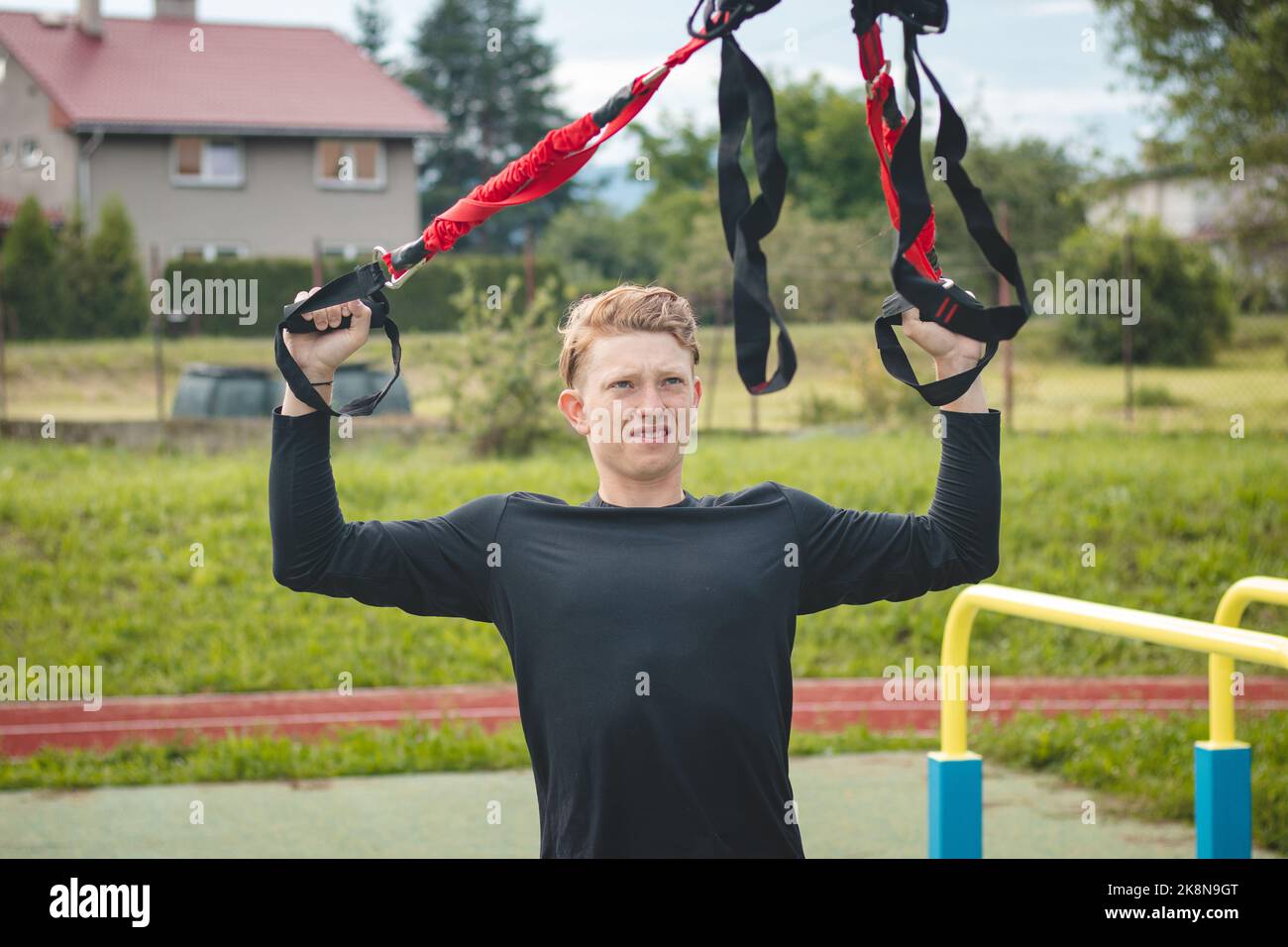 Profisportler streckt und stärkt seine Arme, Schultern und Brustmuskeln mit trx-Fitnessbändern. Unterstützen Sie das Training für maximale Leistung Stockfoto