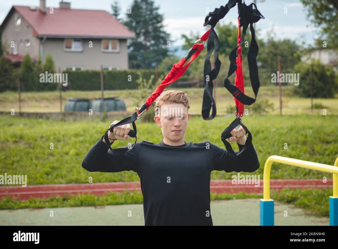 Profisportler streckt und stärkt seine Arme, Schultern und Brustmuskeln mit trx-Fitnessbändern. Unterstützen Sie das Training für maximale Leistung Stockfoto