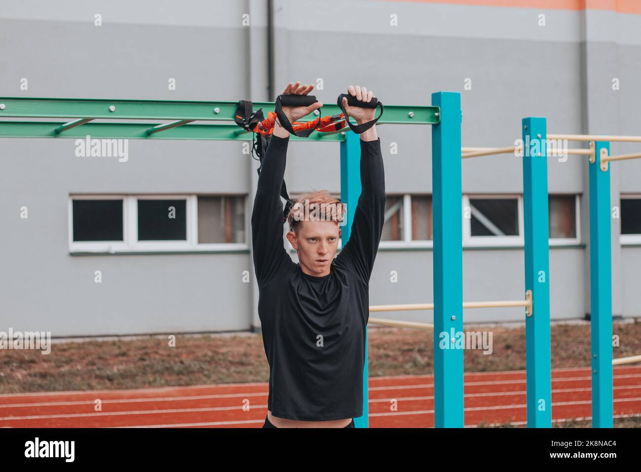 Profisportler streckt und stärkt seine Arme, Schultern und Brustmuskeln mit Total Resistance Übungen Fitnessbänder. Support-Training Stockfoto