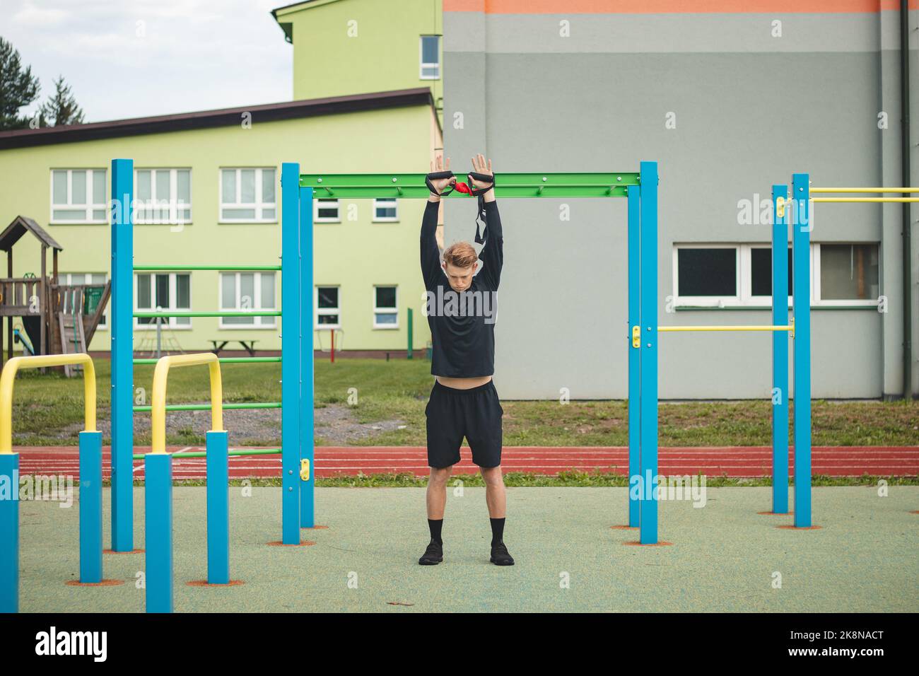 Profisportler streckt und stärkt seine Arme, Schultern und Brustmuskeln mit TRX-Fitnessbändern. Unterstützen Sie das Training für maximale Leistung Stockfoto