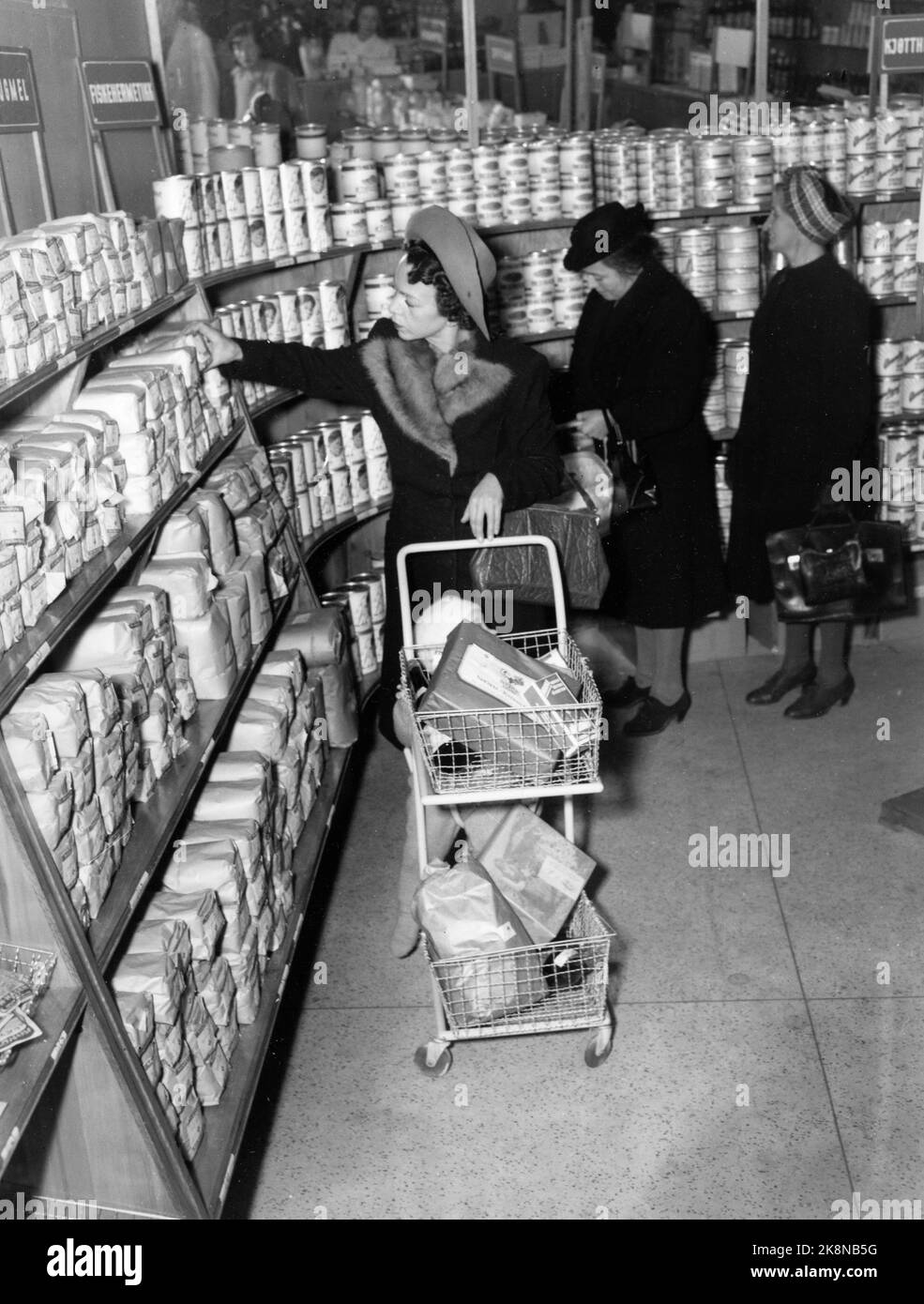 Oslo 1947: Die Rationierung von Waren dauerte lange nach dem Krieg. Hier ist eine junge Mutter, die mit ihrem Kind, das einen Wagen auf dem Wagen hat, Oslos ersten Selbstbedienungsladen besucht, während die Mutter selbst durch die Regale gehen und die Waren, die sie braucht, herausholen kann. Die Ware ist verpackt, Preis und Markenwert sind auf dem Paket. Hier mit einem Einkaufswagen mit Essen. Der norwegische Genossenschaftsverein 'Snarkjøp' / Samvirkelag in Parkveien 65. Foto: Th. Scotaam / Aktuell / NTB Stockfoto