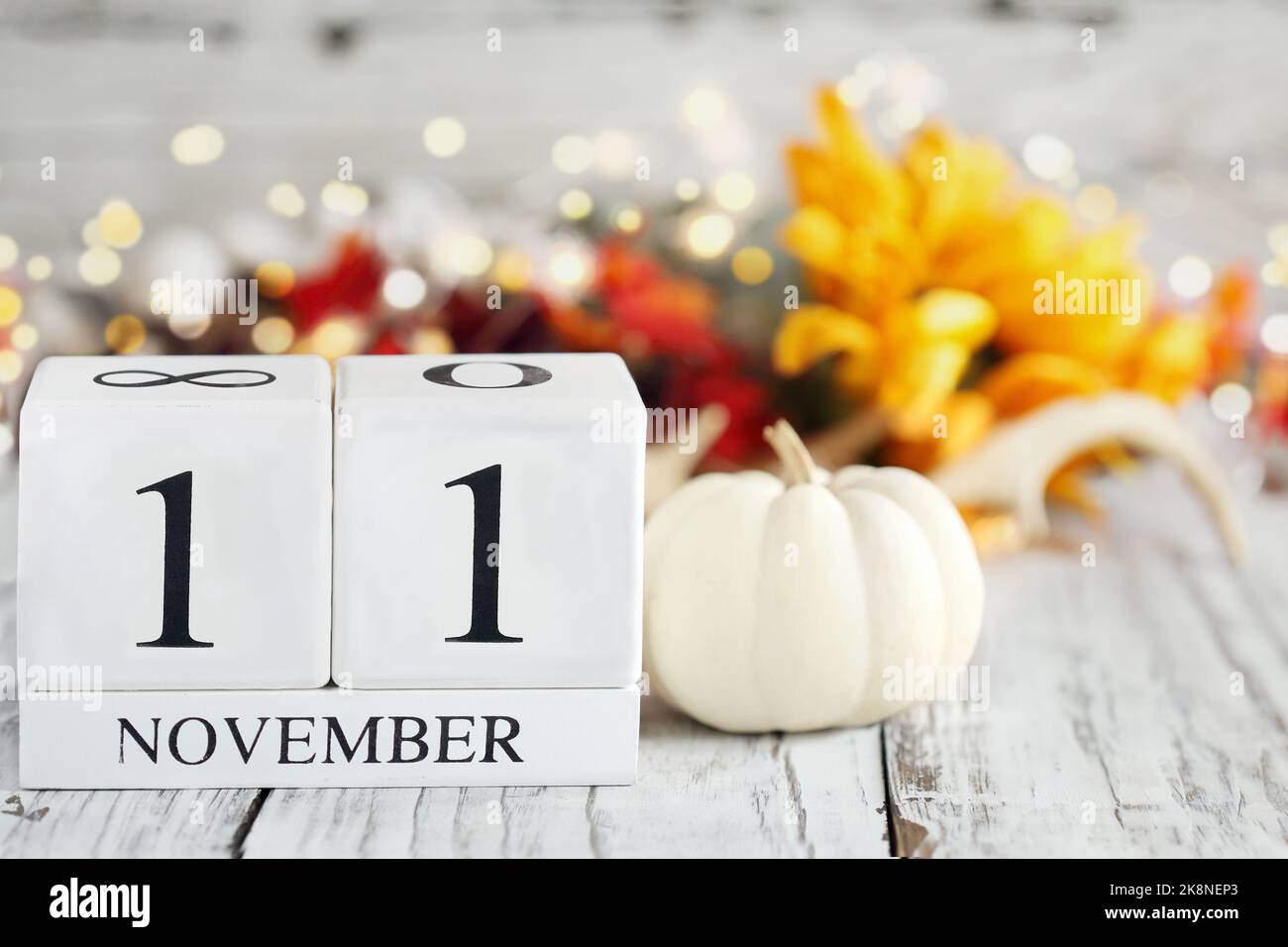 Veteranentag oder Gedenktag. Weiße Holz-Kalenderblöcke mit dem Datum November 11. und Herbstdekorationen über einem Holztisch. Selektiver Fokus. Stockfoto