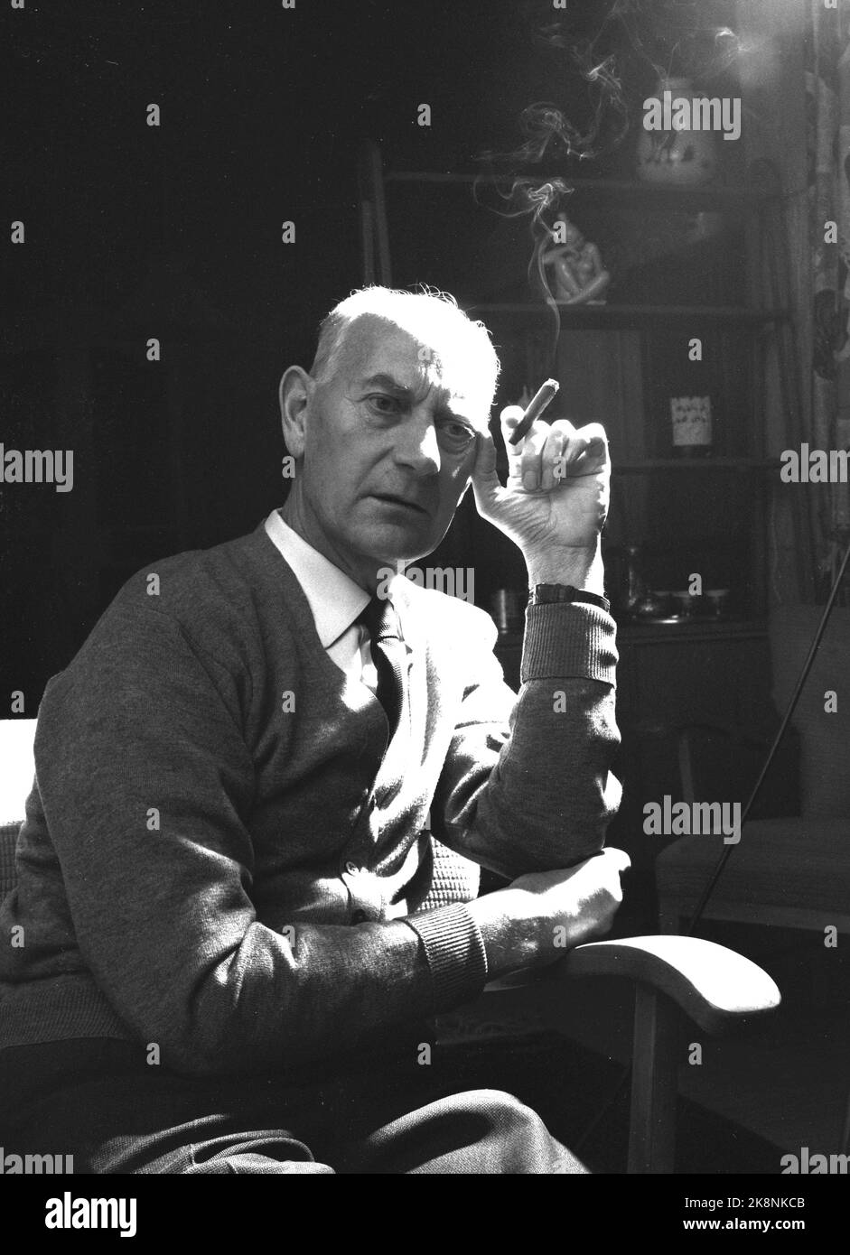 Oslo 195911. Premierminister Einar Gerhardsen lebt nicht in der Residenz des offiziellen Premierministers. Er lebt mit Frau Werna und ihren Kindern in einer Blockwohnung in Sofienberggata. Hier sehen wir Gerhardsen bei einer Zigarre zu Hause im Wohnzimmer entspannen. Ernst. Foto: Aage Storløkken / Aktuell / NTB Stockfoto