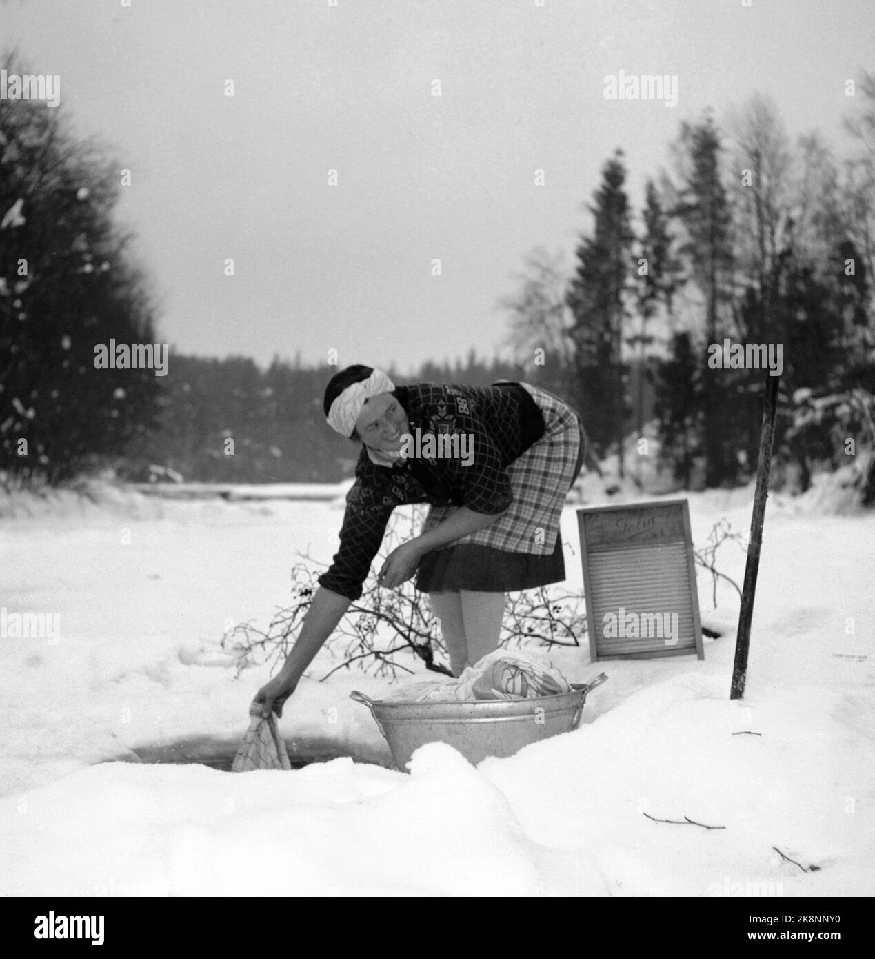 Hedmark im Winter 1948. Wasserknappheit in Ostnorwegen nach der Dürre im Sommer 1947. Die Betriebe müssen Wasser in den Flüssen holen oder Wasser aus den Molkereien fließen lassen. Hier wäscht eine Frau die Kleidung in einem Bach, durch ein Loch, das im Eis gehackt wird. BALL mit Kleidung und Waschbrett. Foto: Børretzen / Aktuell / NTB Stockfoto