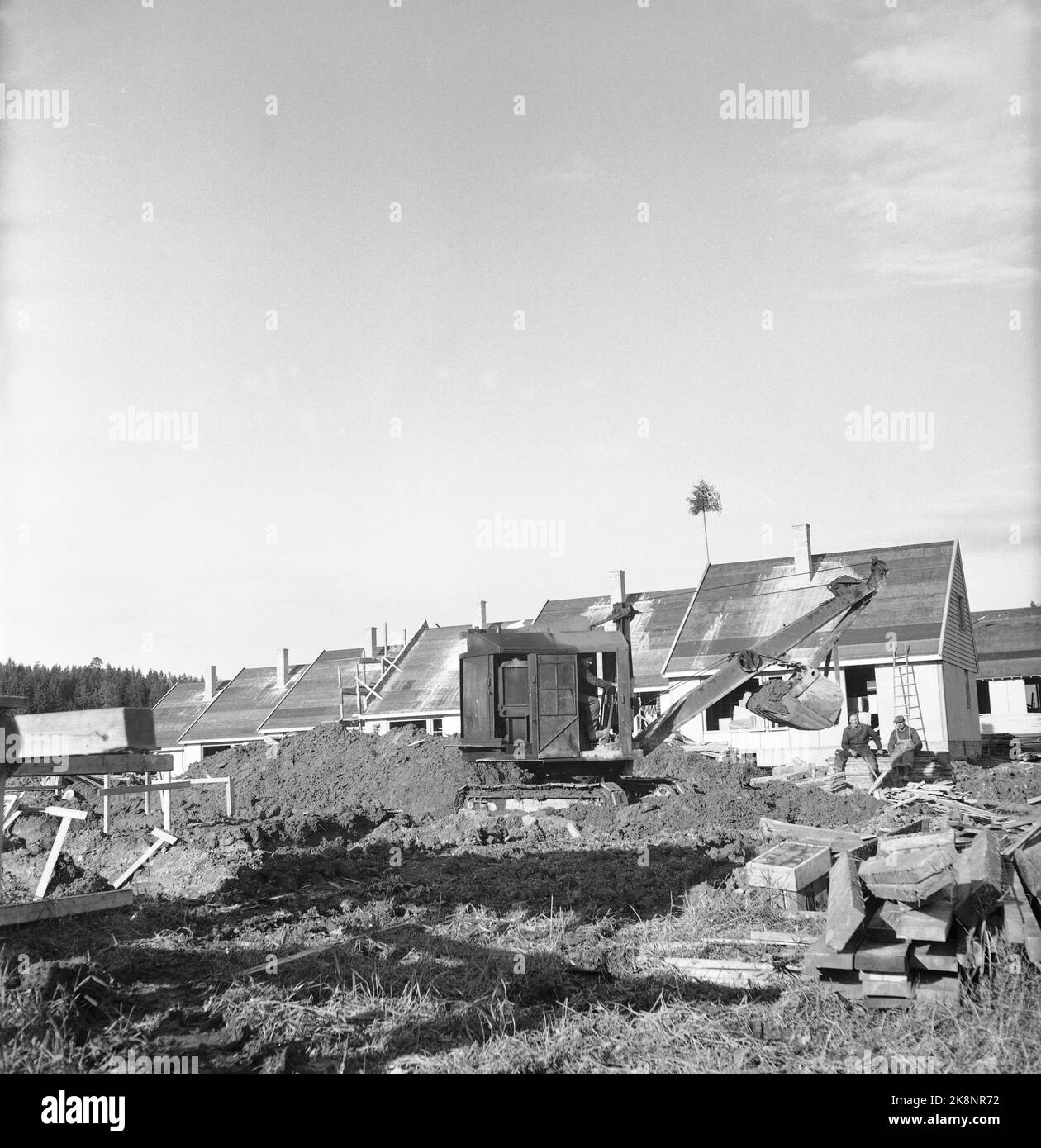 Bærum. Nadderud 1951. Auf Nadderud werden 48 Häuser gebaut. „Es wird von Stadthäusern auf der eineinhalb Etage gesprochen, die nach amerikanischen Prinzipien eingerichtet sind. Jede Wohnung ist in 4 Zimmern und Küchen, mit einer Gesamtfläche von ​​115, neben dem Keller unter der Hälfte des Hauses. Die Miete wird 160.- Kronen pro Monat betragen, kann aber wahrscheinlich reduziert werden. Die Kaution wird auf NOK 7.000 pro Wohnung geschätzt. Hier ist ein alter Bagger vor den Häusern. Foto: Sverre A. Børretzen / NTB Stockfoto