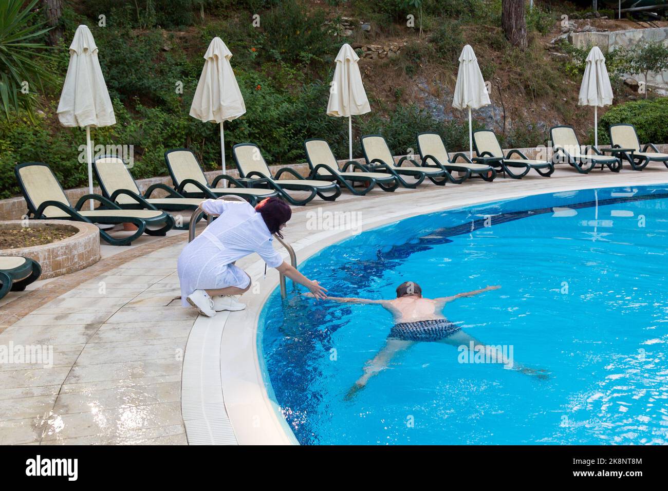 Eine Ärztin im weißen Mantel zieht einen ertrunkenen Mann aus dem Pool. Stockfoto