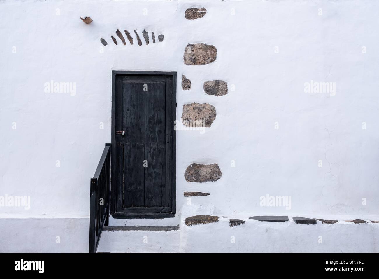 Rustikale schwarze Holztür in verwitterter weißer Wand Stockfoto
