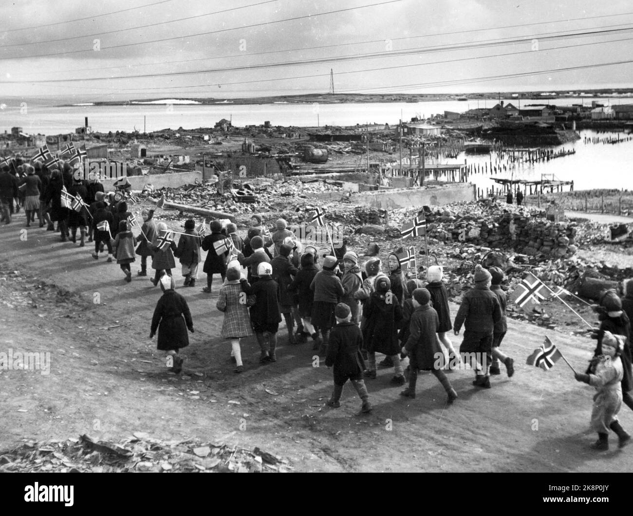 Vadsø19450517: Der erste Mai 17 nach dem Zweiten Weltkrieg wird in Vadsø mit Kinderzügen gefeiert. Kinder mit Fahnen. Ruinen von zerbrochenen Gebäuden im Hintergrund. Foto: NTB / NTB Stockfoto