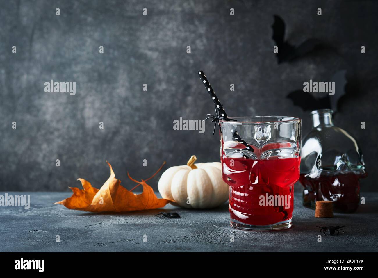 Blutiger Halloween-Cocktail. Blutig roter Cocktailglas-Becher für Halloween und Flaschenform Totenkopf auf dunklen Hintergründen. Halloween-Party mit Süßigkeiten Augen, Stockfoto