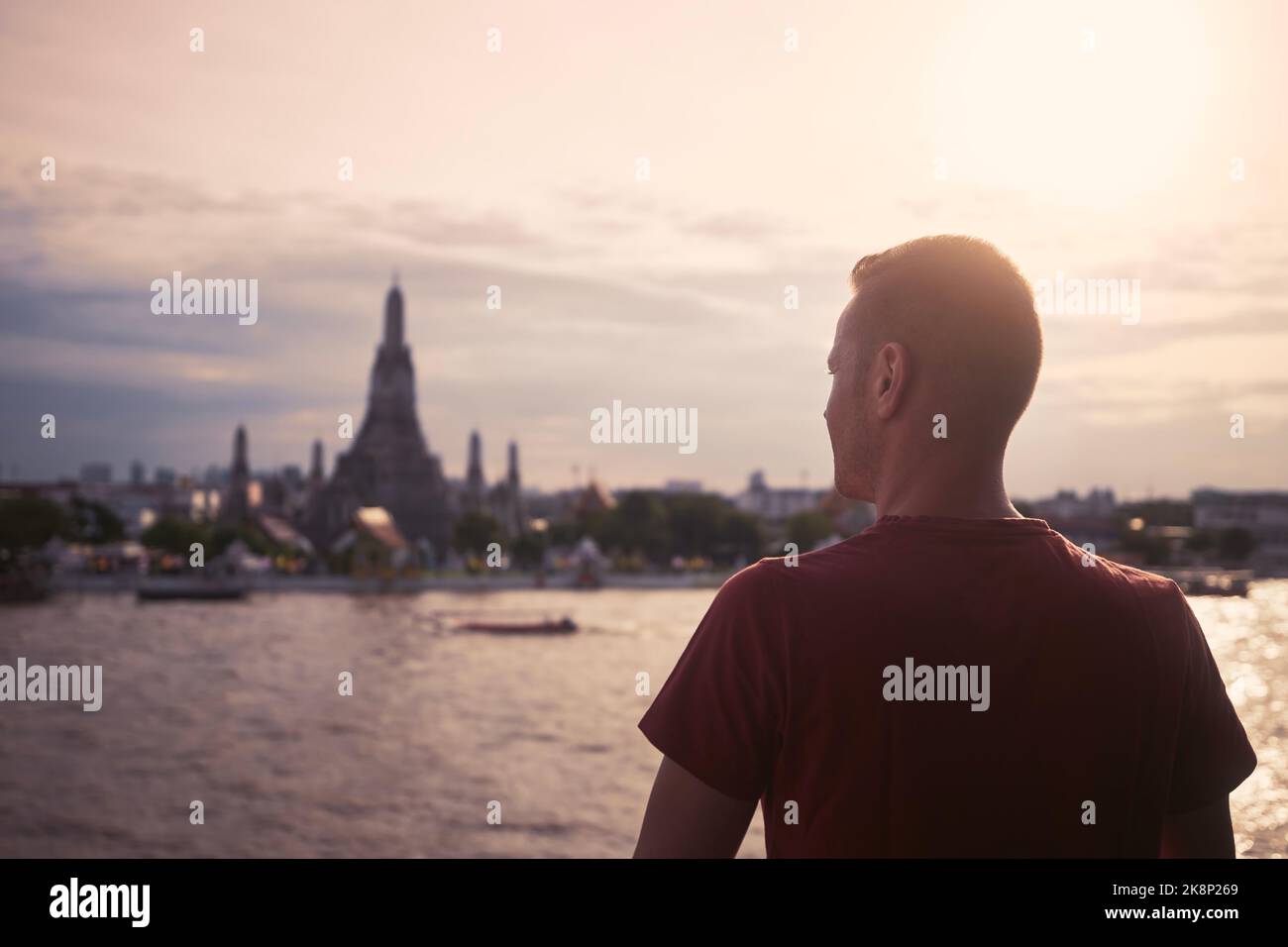 Rückansicht des Touristen gegen Stadtbild mit Chao Phraya River und Wat Arun bei schönem Sonnenuntergang. Bangkok, Thailand. Stockfoto