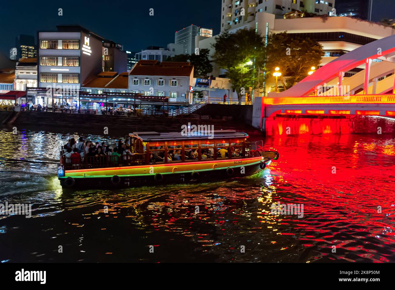 Ein Touristenboot, das nachts unter der Elgin Bridge auf dem Singapore River vorbeifährt Stockfoto