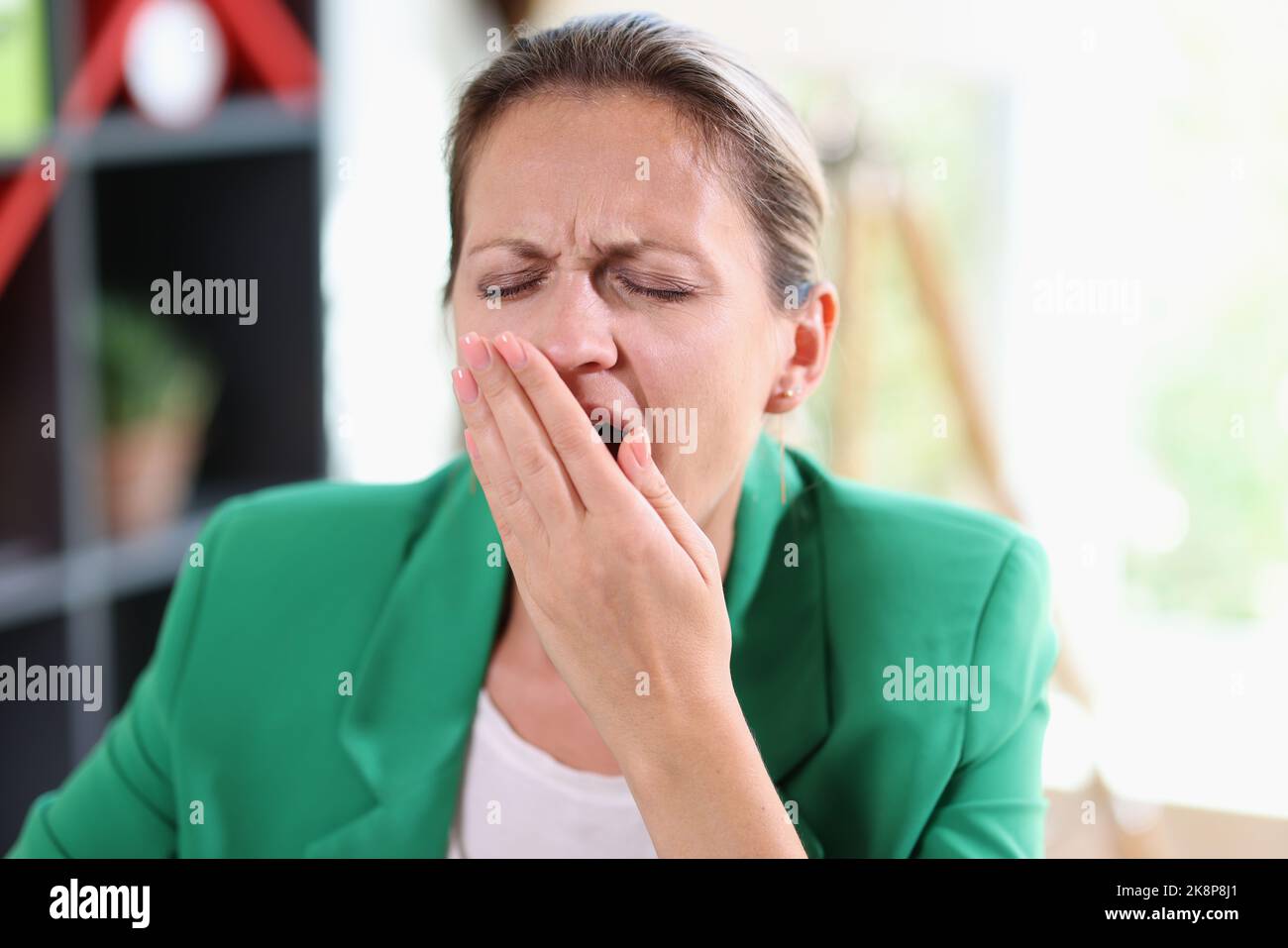 Überarbeitete müde Geschäftsfrau gähnend und Gesicht mit der Hand bedeckend Stockfoto