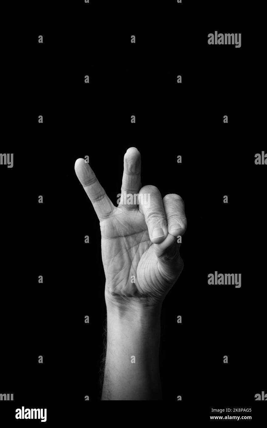Dramatisches Schwarz-Weiß-Bild einer männlichen Hand, die den japanischen Zeichennachsbuchstaben „TSU“ oder „っ“ vor einem dunklen Hintergrund mit Kopierer-Spac schreibt Stockfoto