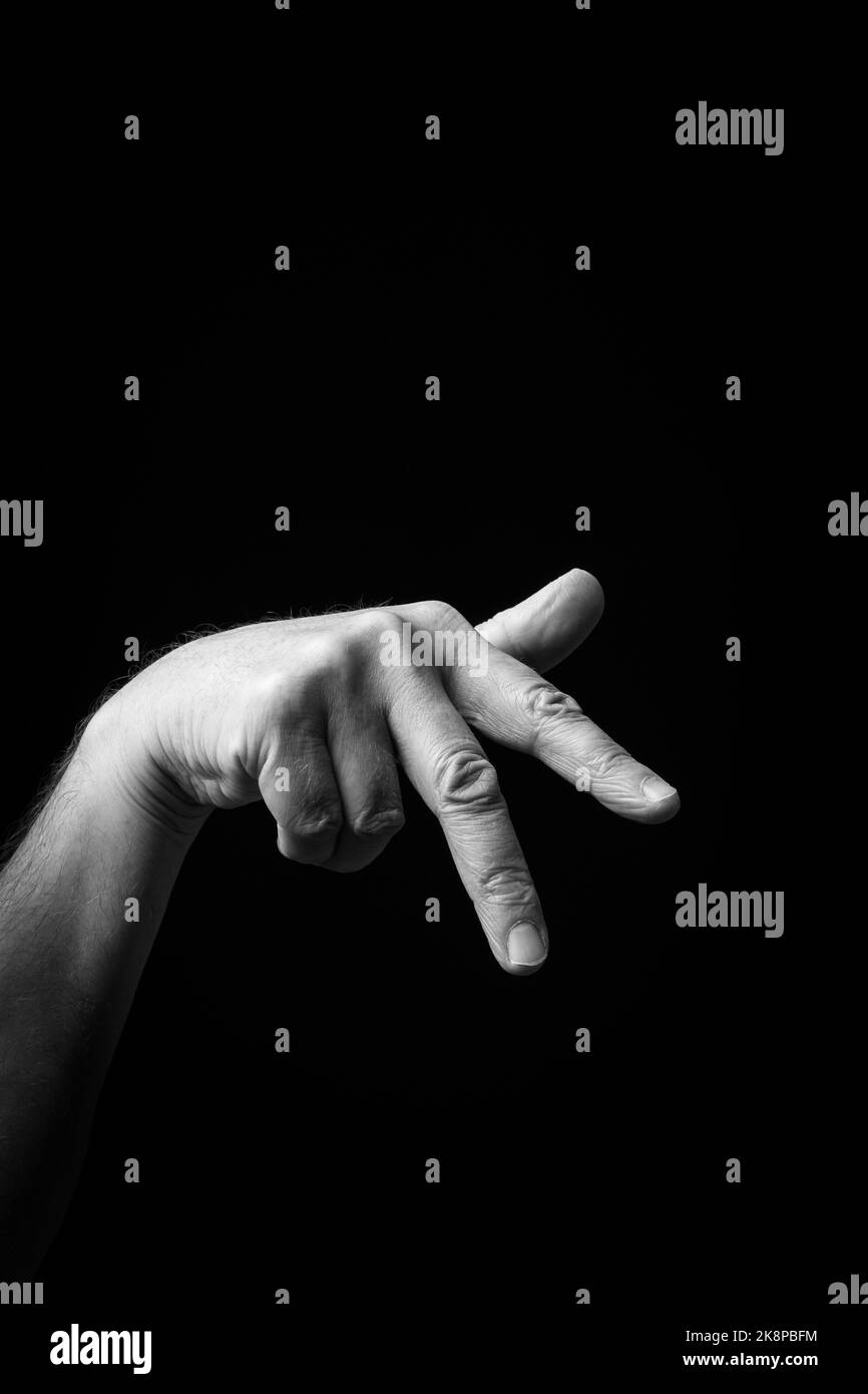 Dramatisches Schwarz-Weiß-Bild einer männlichen Hand, die den japanischen Zeichennachsbuchstaben „SU“ oder „す“ vor einem dunklen Hintergrund mit Kopierfläche schreibt Stockfoto