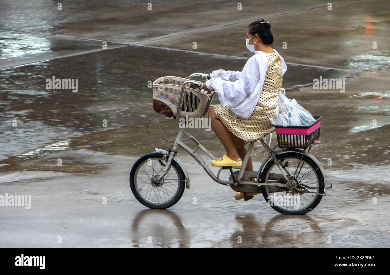 SAMUT PRAKAN, THAILAND, Okt 03 2022, Eine Frau fährt mit einem Regenmantel ein Fahrrad Stockfoto