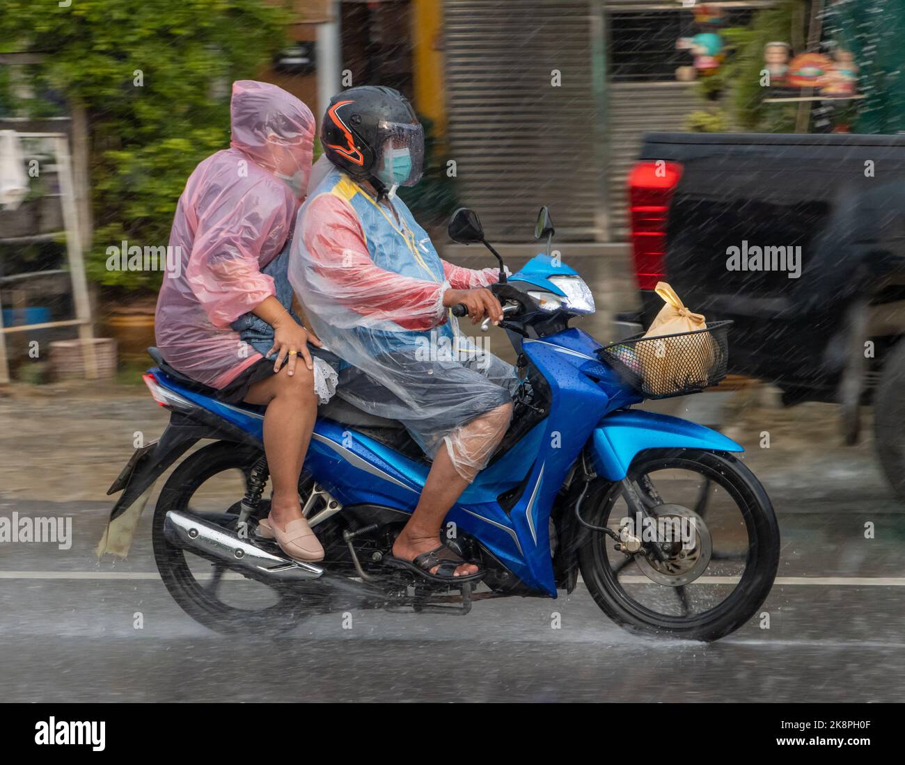 Mototaxi fährt mit einem Passagier bei starkem Regen, Thailand Stockfoto