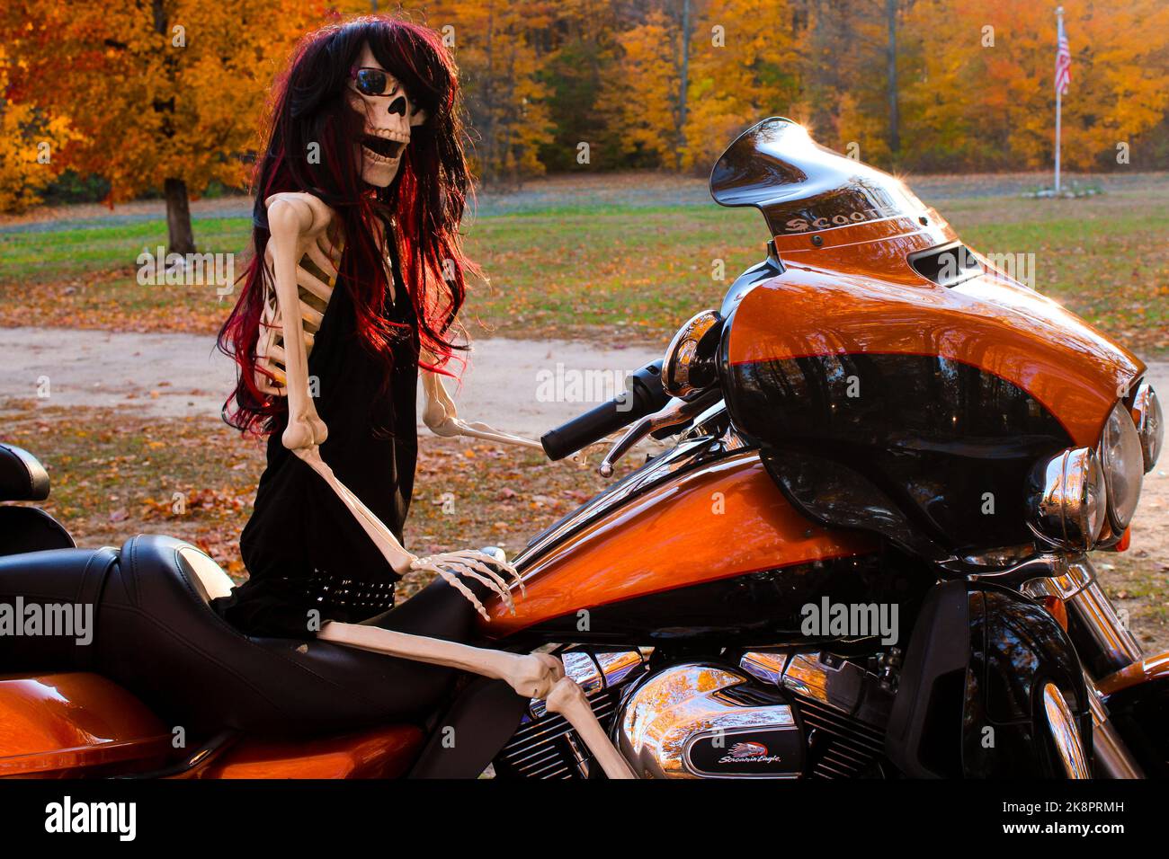 Weibliches Skelett, das im Herbst auf einem Motorrad sitzt Stockfoto