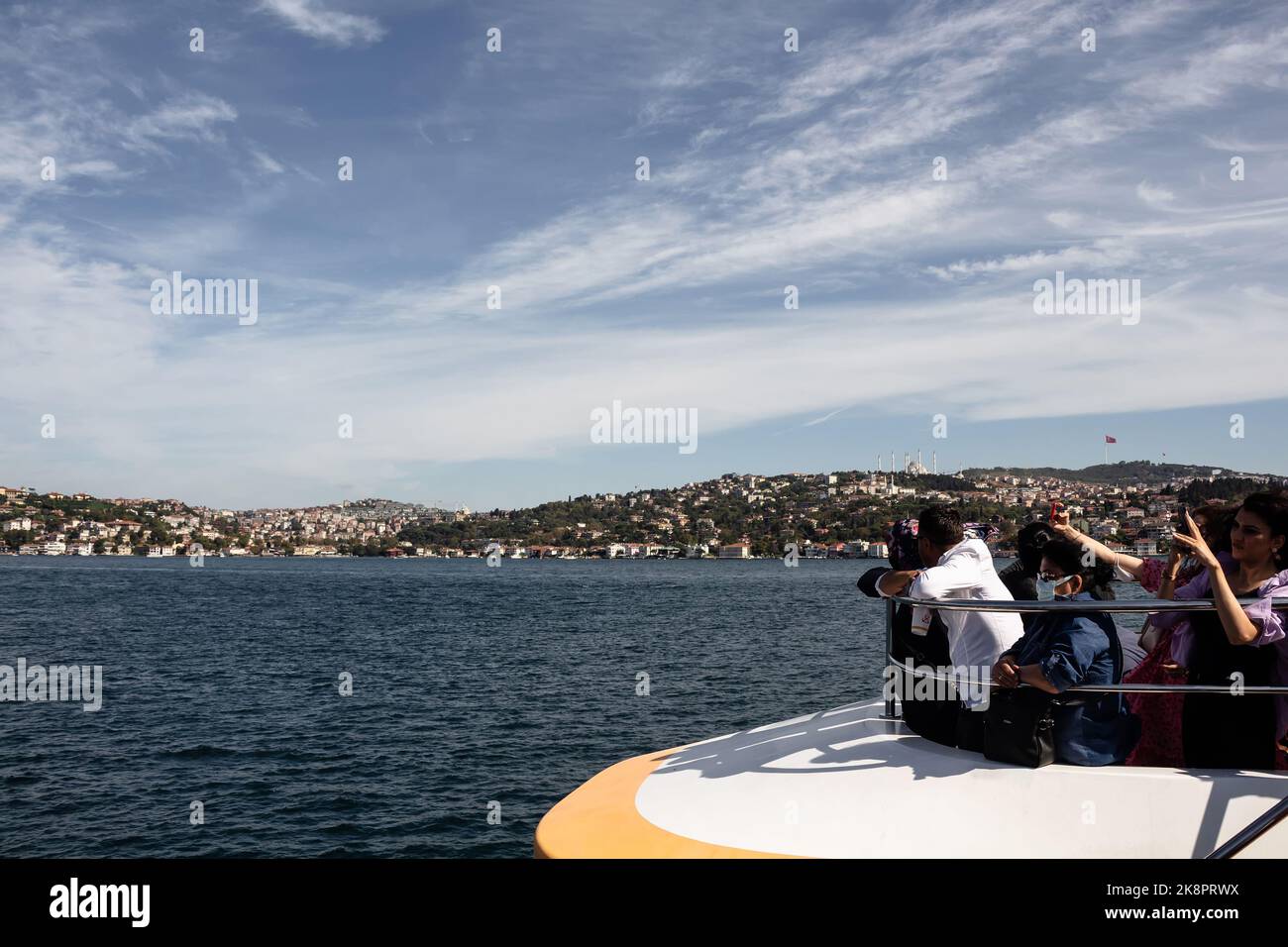 Blick auf Touristen auf einem Kreuzfahrtboot auf dem Bosporus und der asiatischen Seite Istanbuls. Es ist ein sonniger Sommertag. Stockfoto
