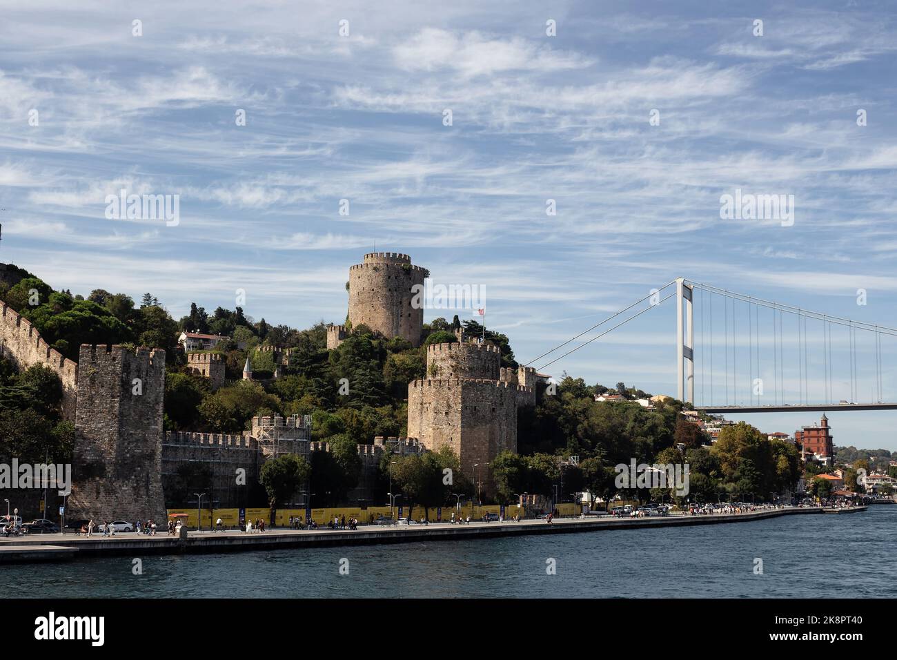 Blick auf Menschen, die am Bosporus, der historischen Festung Rumeli Hisari und der FSM-Brücke in Istanbul, vorbei gehen. Es ist ein sonniger Sommertag. Schöne Reise s Stockfoto