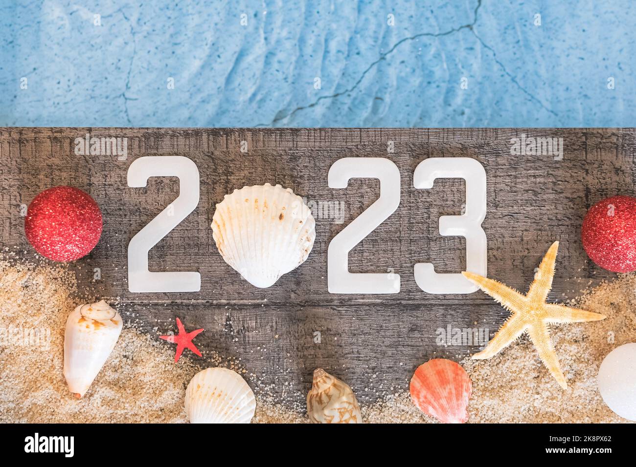 Frohes neues Jahr 2023 Konzept mit einer Schale und einem Seestern am Pool. Winterurlaub in der Sonne. Stockfoto