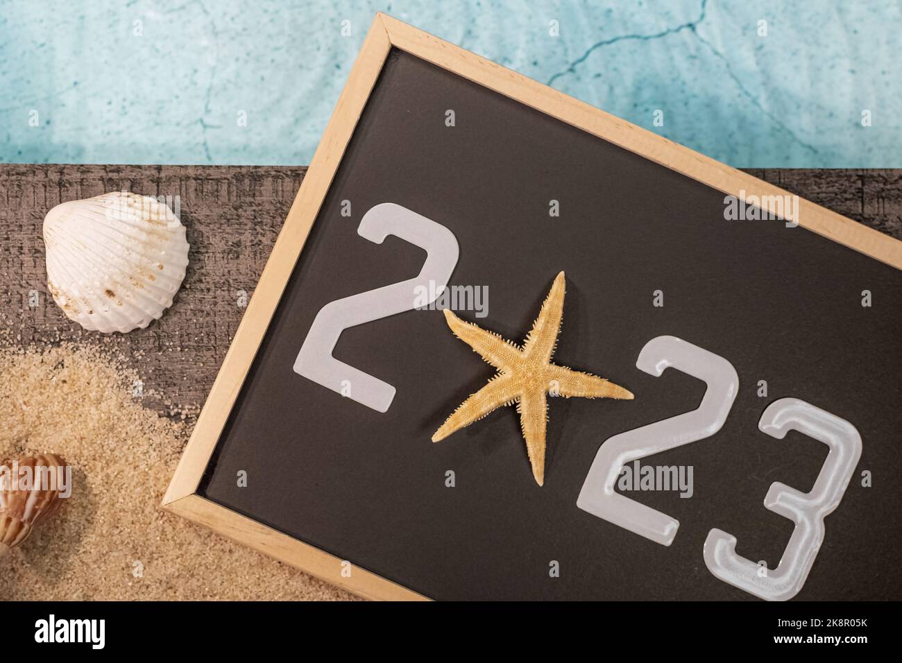 Frohes neues Jahr 2023 Konzept mit einer Schale und einem Seestern am Pool. Winterurlaub in der Sonne. Stockfoto