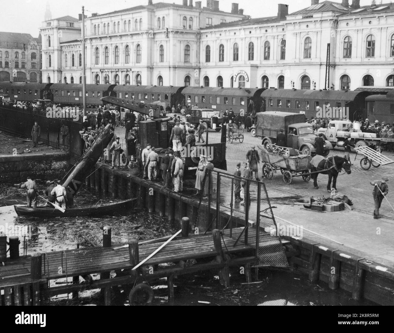Oslo 19411004 Englische Flugzeuge, die bei der Ostbahn abgeschossen wurden, werden hier vom Meer angehoben. Das Leben der Menschen auf dem Pier. Pferd und Wagen. Zugwaggons im Hintergrund. Foto; Aage Kihle / NTB Stockfoto