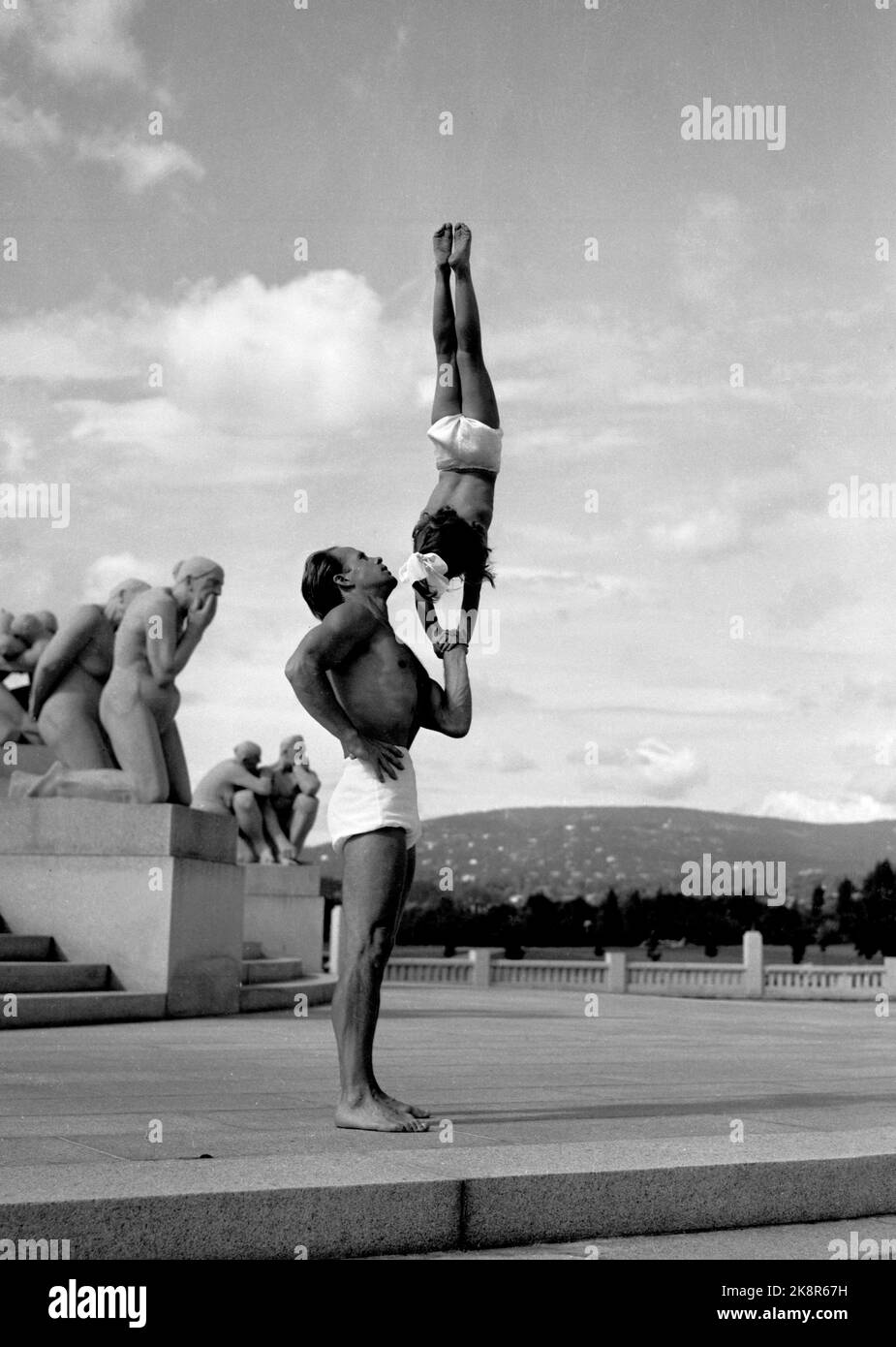 Oslo 19490815 Sportunterricht wurde nach dem Krieg wichtig - und der Turner und Friskport-Anwalt Odd Bye-Nielsen führte seine eigene Akademie für Körperkultur, wo er vor allem Kinder ausbildete, bis zum Alter von vier Jahren. Einige der Kinder traten im Sommer mit ihm im Casino auf. Hier hat er einige der Kinder in den Frogner Park aufgenommen. Eines der kleinen Mädchen steht auf den Händen von Nielsens Arm. Vigelands Skulpturen sehen aus, als ob sie nicht ihre eigenen Augen denken .. Foto: NTB / NTB Stockfoto