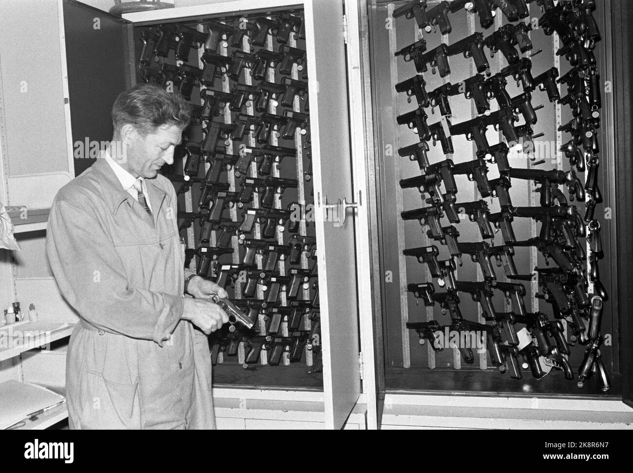 Oslo 17 November 1962 "Eine Bank wird ausgeraubt" wie funktioniert der moderne Detektiv? Wie funktioniert das Kriminalpolizeizentrum, wenn eine Bank ausgeraubt wird? Hier; -Polizist Johan Hageløkken vor einer beeindruckenden Waffensammlung in der Laborabteilung. Es gibt Waffen von praktisch allen Arten und Kalibern, und es macht überhaupt keinen Spaß, zwei Schränke voll solcher Waffen zu haben. Es ist etwas zu haben, mit dem man vergleichen kann, wenn Strafverfahren auftreten, in denen Waffenkugeln eine Rolle spielen. Dann ist es wichtig, die Waffe zu finden. Foto: Ivar Aaserud / Aktuell / NTB Stockfoto