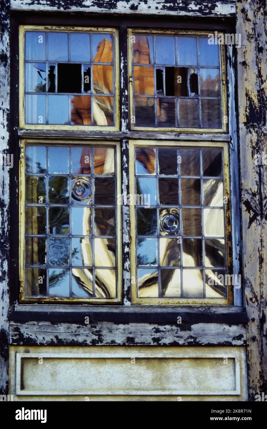 Fenster eines Fachwerkhauses mit kleinen Rahmen mit Spiegelung eines Hauses. Sehr altes Glas. Atmosphärisches Bild. Stockfoto