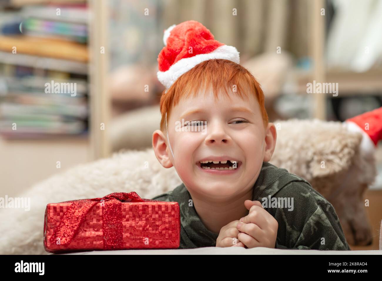 Ein junger rothaariger Junge lacht fröhlich in einem Neujahrshut. Stockfoto