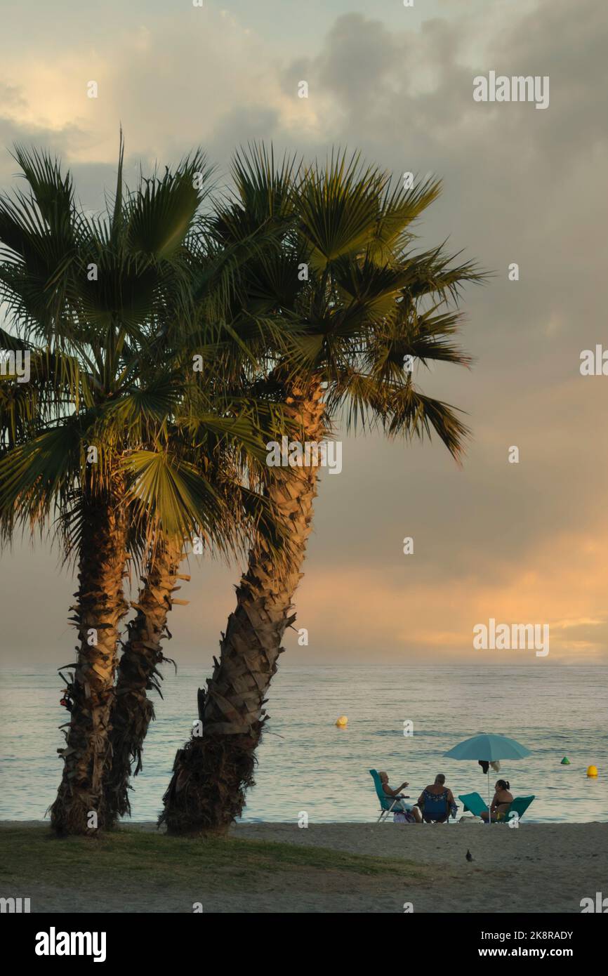 La Cala de Mijas, Costa del Sol, Provinz Malaga, Andalusien, Südspanien. Eine Gruppe von Leuten, die die Nachmittagssonne am Strand genießen. Stockfoto