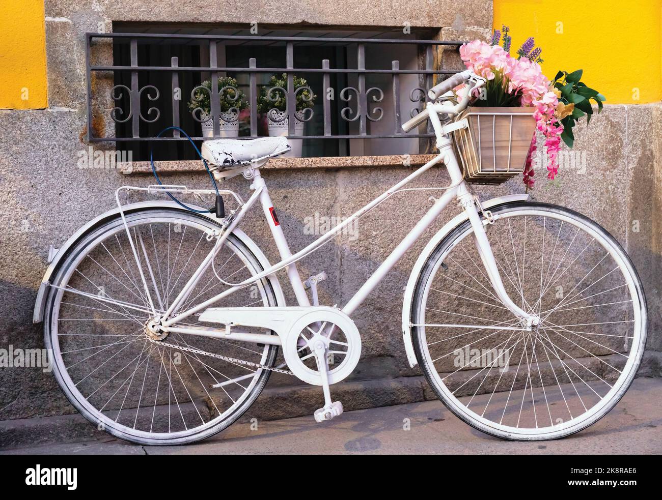 Das Weiße Fahrrad. Altes Fahrrad, weiß lackiert, Blumen im Warenkorb unter Lenker. Fotografiert in Matosinhos, Portugal. Stockfoto