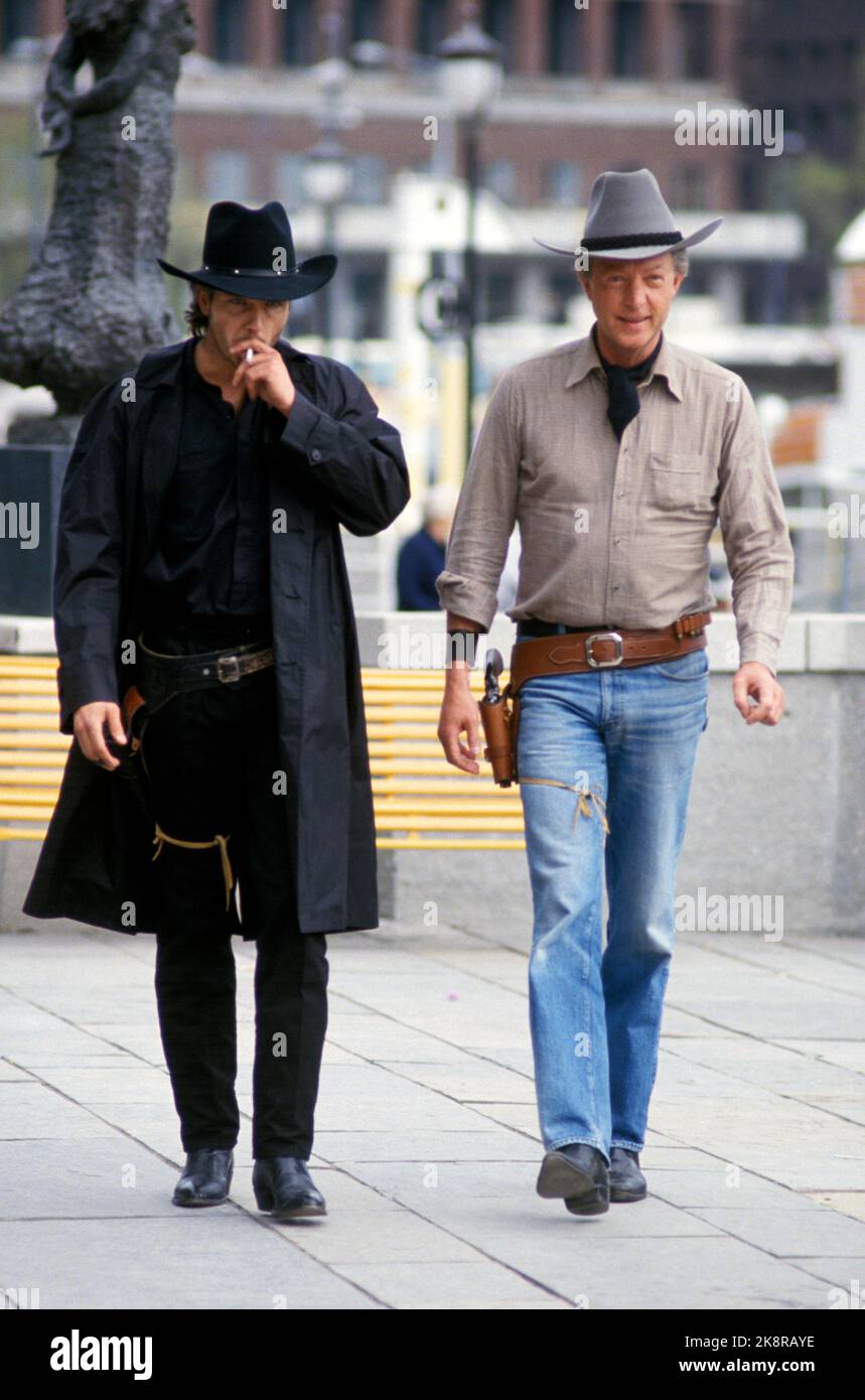 Oslo 1987-05: Dreharbeiten zu den Büchern über 'Morgan Kane'. Morgan Kane wird im Kino zu sehen sein. Insgesamt wurden 21 Millionen Exemplare der Morgan Kane-Bücher verkauft, und zwei von ihnen, „El Gringo“ und „El Gringos Rache“, sollen gefilmt werden. Das Bild zeigt den Schauspieler Jim Young, der am 5. Mai 1987 in Norwegen Morgan Kane spielen wird, um den Film im Vorfeld zu promoten. Hier mit dem Autor Kjell Hallbing (t.h.), - beide in Cowboy-Ausrüstung, mit Cowboy-Hut, Cowboy-Stiefeln und Revolvergurten. (Die Pläne für die Dreharbeiten zu den Morgan Kane Büchern wurden jedoch nicht umgesetzt ...) Foto: Henrik Laurvik / NTB Stockfoto