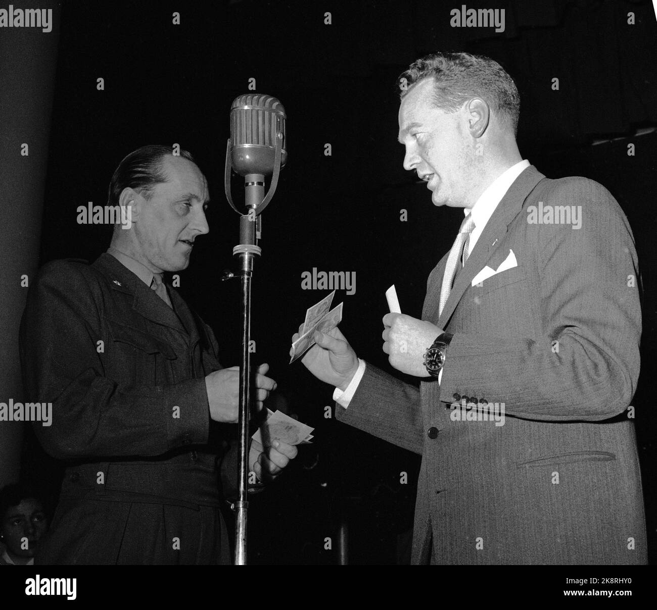 Oslo 1955 NRK Radio hat einen großen Erfolg mit dem Fragebogen "die Frage" von dem großen Glas Rolf Kirkvaag geführt. Das Konzept ist einfach und die Preise sind bescheiden, aber die Stimmung im Studio ist am Siedepunkt! Hier Kirkvaag in Aktion mit einem der Teilnehmer, Fenrik Arvid Paulsen aus Rena. „Geht es weiter?“ Kirkvaag fragt. Foto: Storløkken / Aktuell / NTB Stockfoto