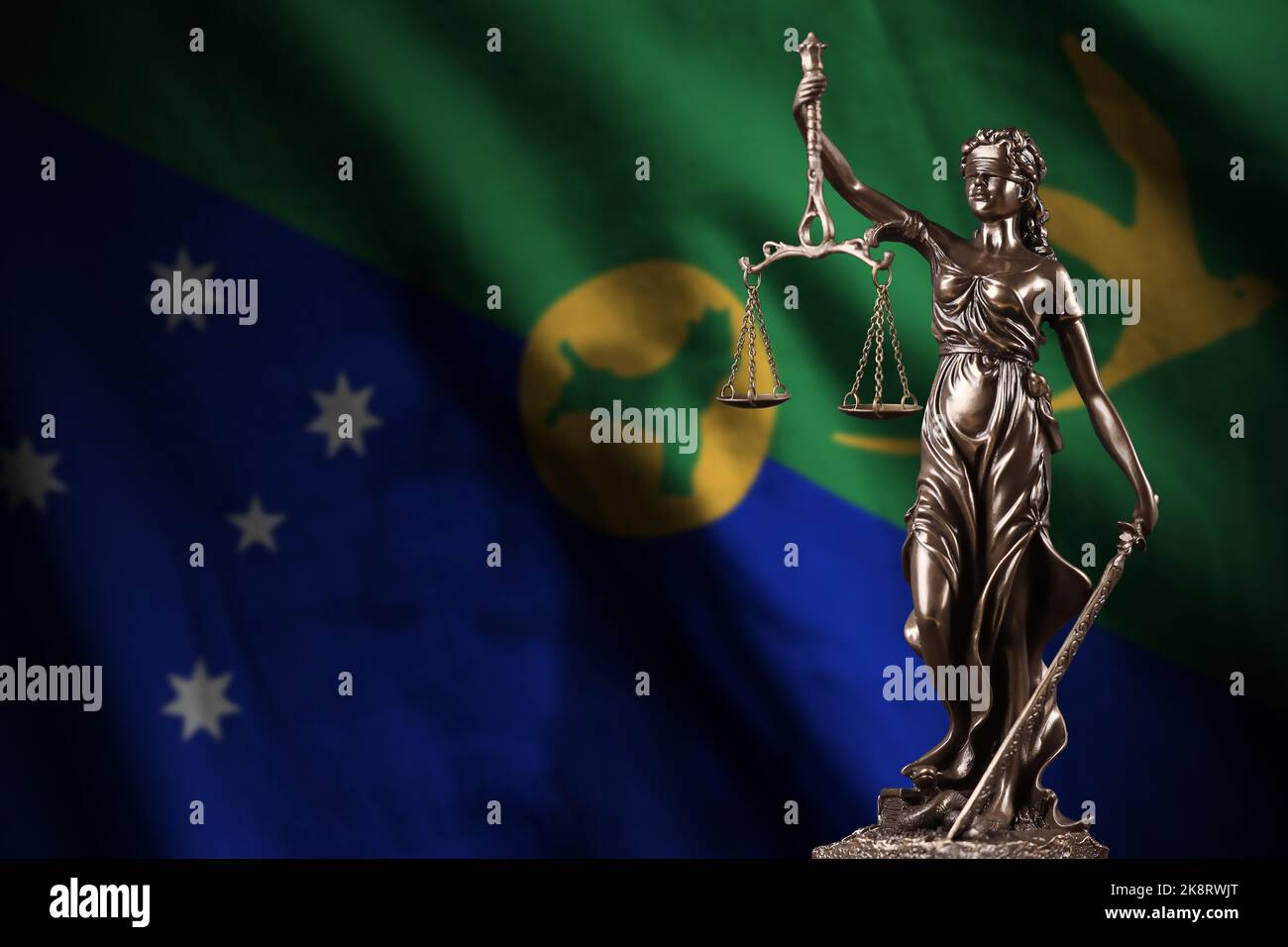 Weihnachtliche Inselflagge mit Statue der Justizdame und Justizwaagen im dunklen Raum. Konzept von Urteil und Bestrafung, Hintergrund für Jurythemen Stockfoto