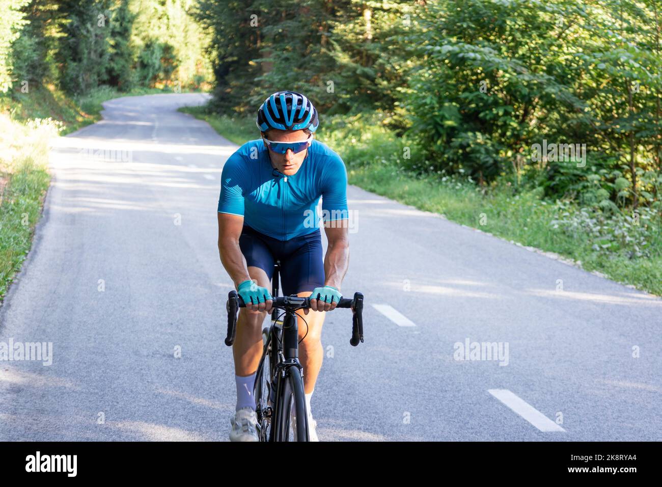 Kaukasischer Rennradfahrer, der auf einer offenen Radroute bergauf fährt Stockfoto