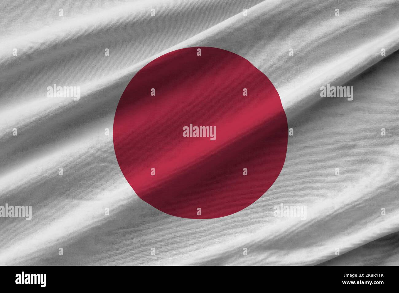 Japan Flagge mit großen Falten winken aus nächster Nähe unter dem Studiolicht im Innenbereich. Die offiziellen Symbole und Farben in Stoff Banner Stockfoto